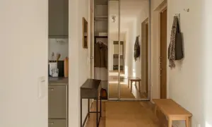 En hall med en träbänk, en smal konsol och en stor spegelgarderob. Hållbar inredning med naturliga material som jute och trä.