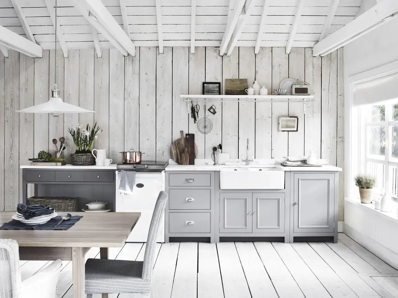 Ljust och luftigt kök med vit inredning inspiration. Träpaneler på väggar och tak, gråa skåp och en vit diskho.