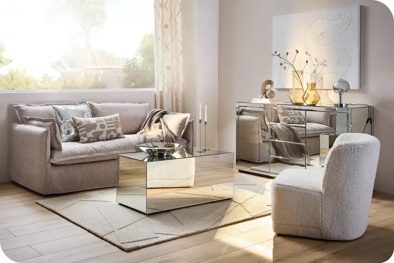 En ljus och lyxig soffgrupp med spegelbord och en fluffig fåtölj. En modern tolkning av 90 tals inredning med fokus på glamour och komfort.