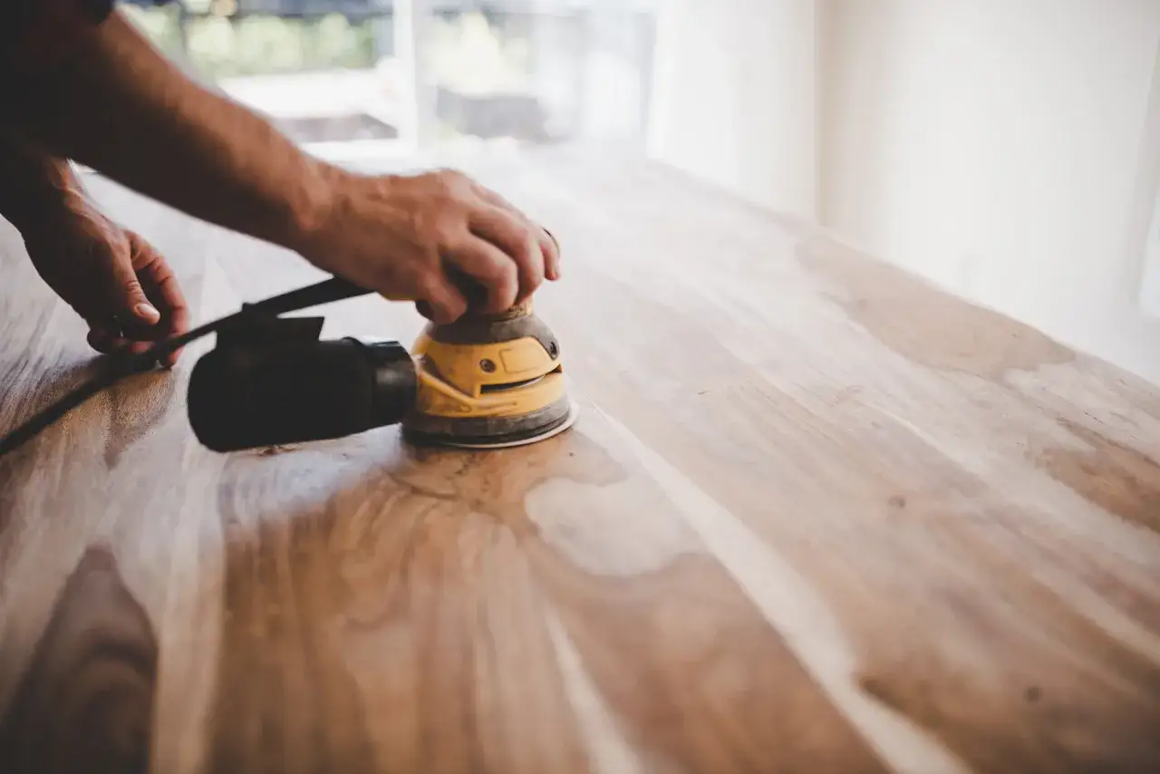 H&auml;nder slipar ett lacka ekbord med en excenterslip.