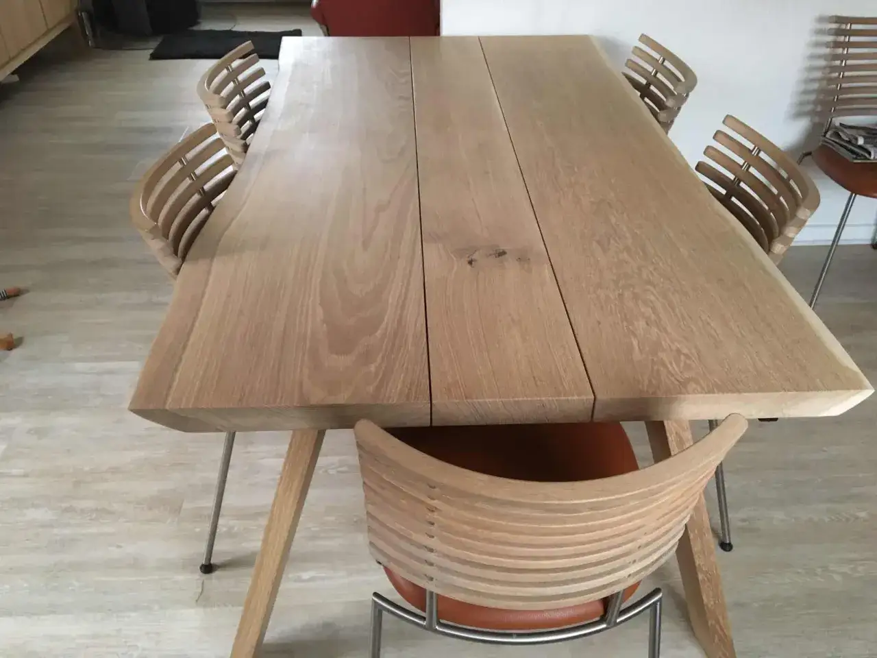 Ett modernt ekbord med en naturlig, pigmenterad oljeyta, omgivet av stilrena stolar med tr&auml;ribbor och l&auml;dersits.