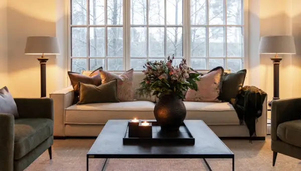 Mysig lounge med soffa och gröna artwood fåtöljer. Blommor, ljus och en filt skapar en varm atmosfär.